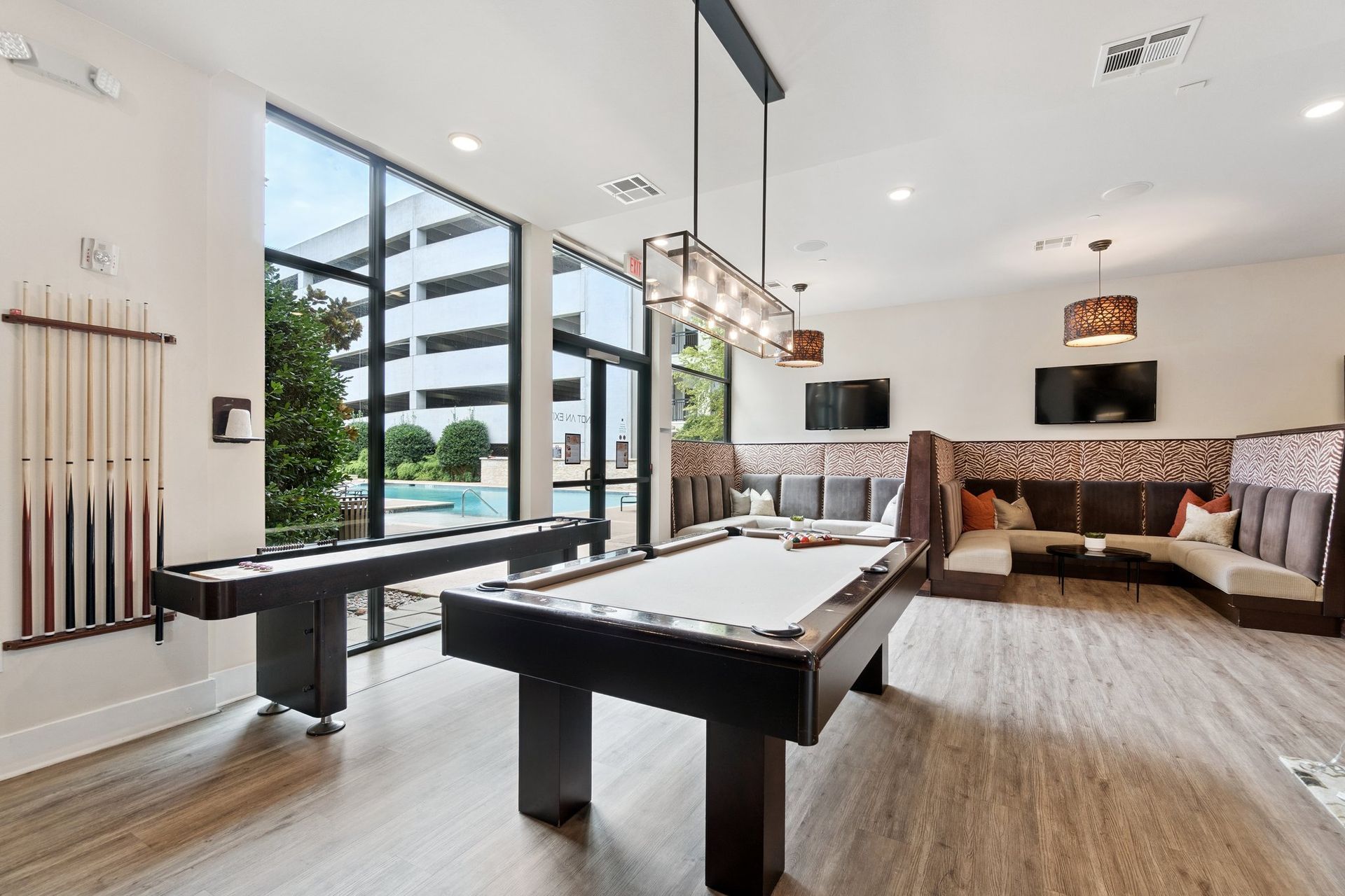 Game room with pool table, air hockey, and lounge seating near windows.
