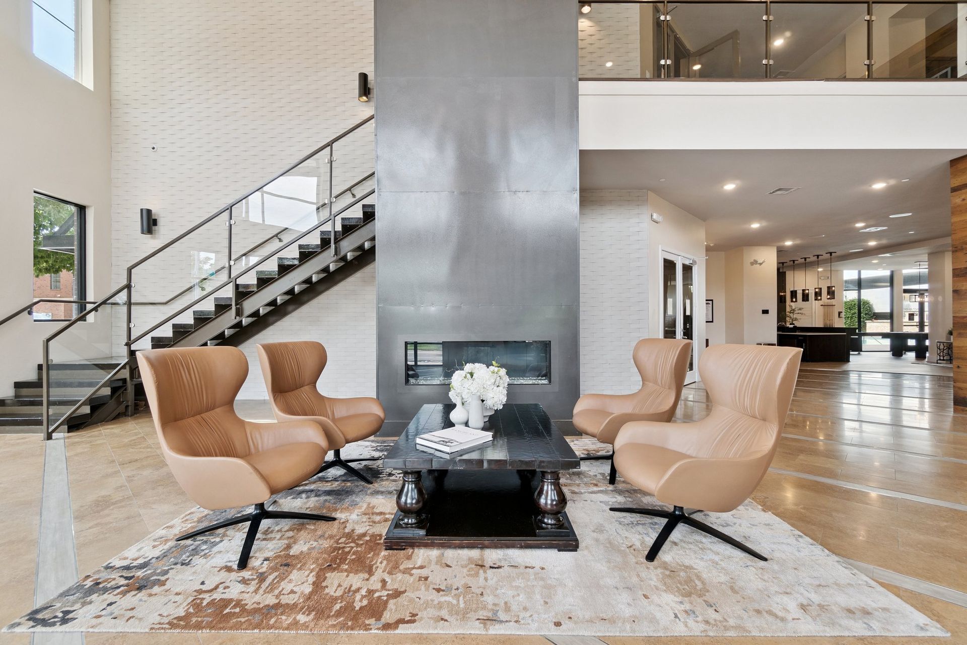 Lobby with modern chairs around a fireplace, stairs, and a second floor.