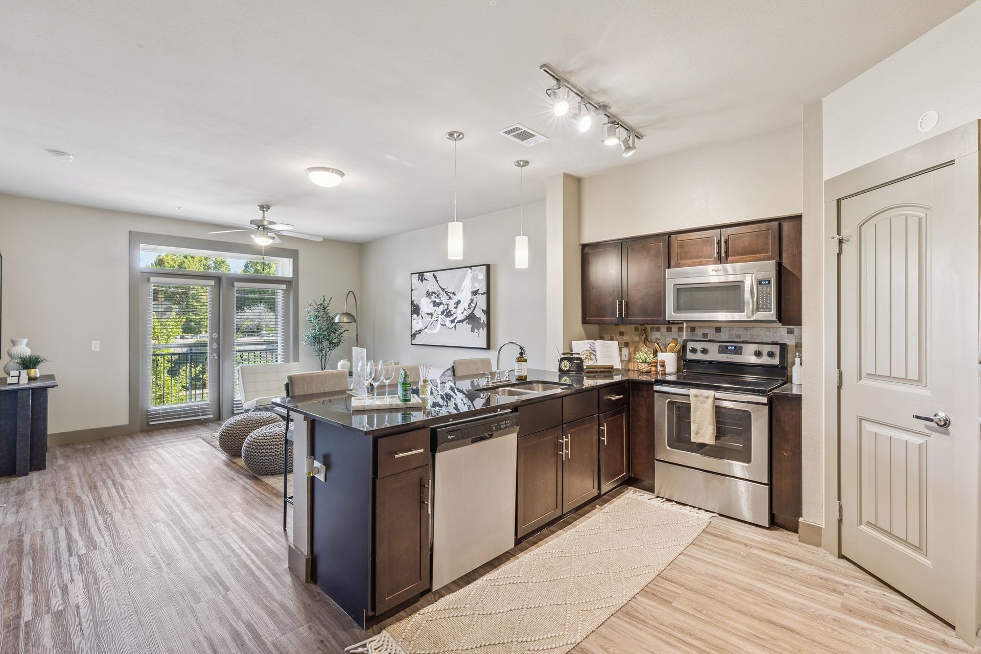 Modern kitchen with stainless steel appliances, dark cabinets, granite island, and wood floors.