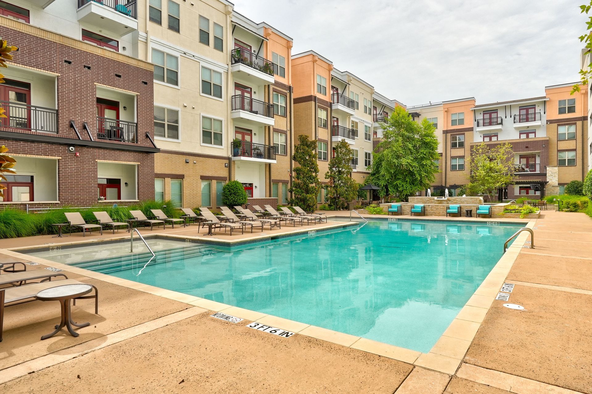 A large swimming pool in front of a large apartment building.