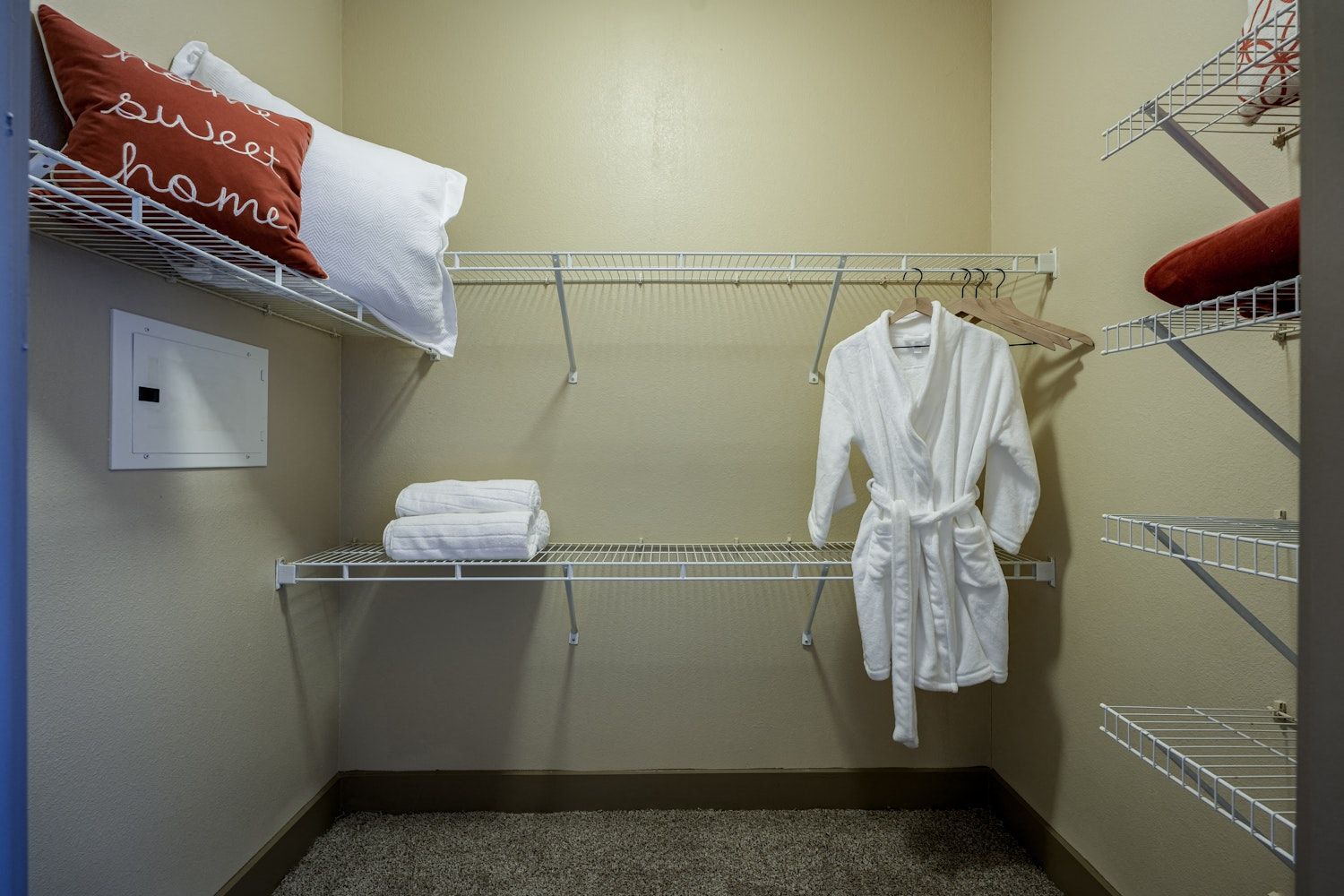A walk in closet with a robe hanging on the wall.