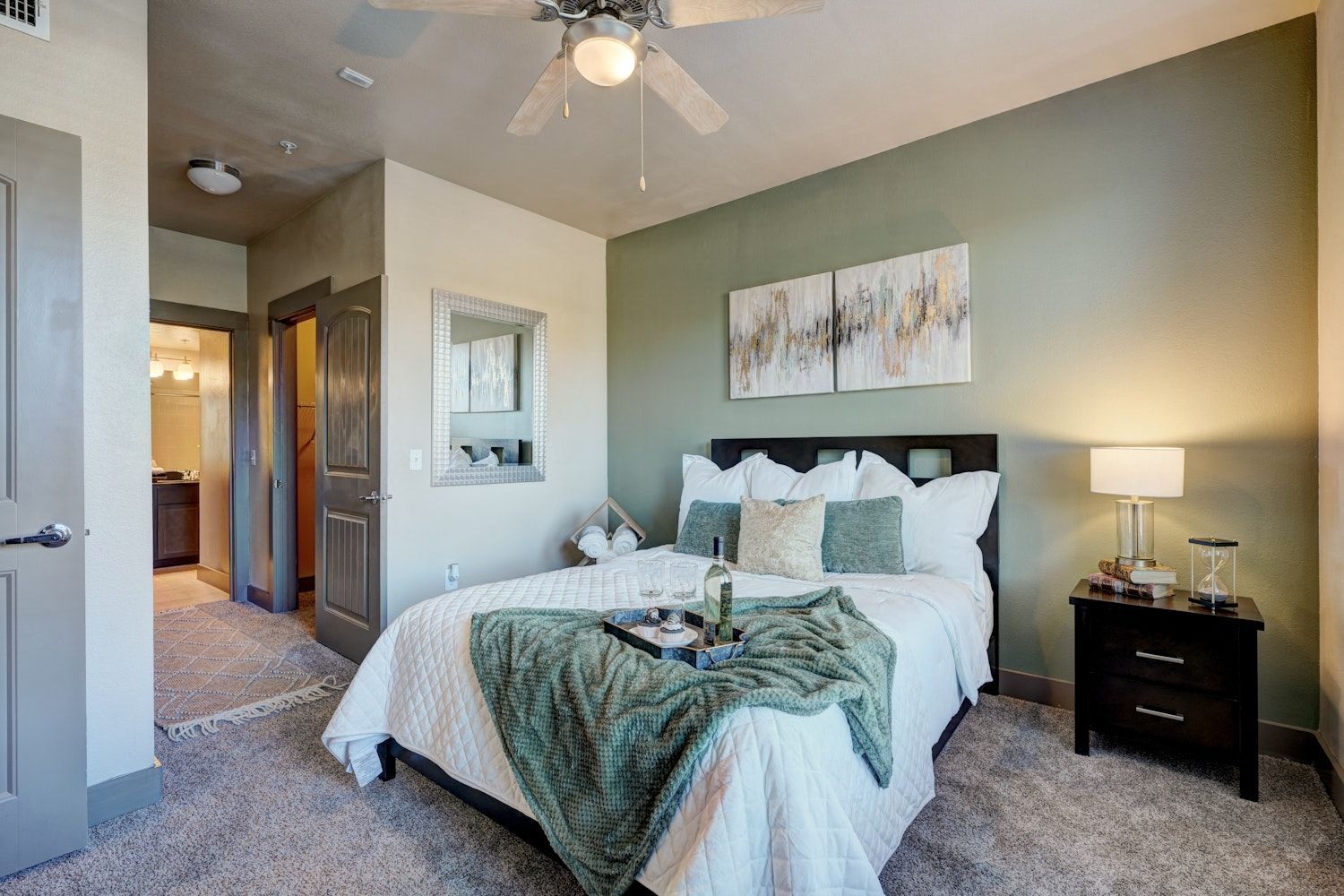 A bedroom with a bed, nightstand, lamp, and ceiling fan.
