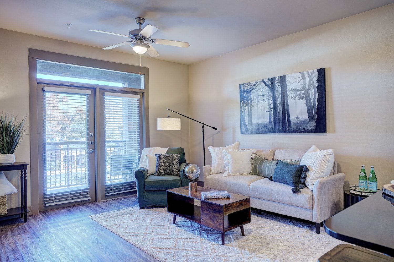 A living room with a couch, chair, coffee table, and ceiling fan.