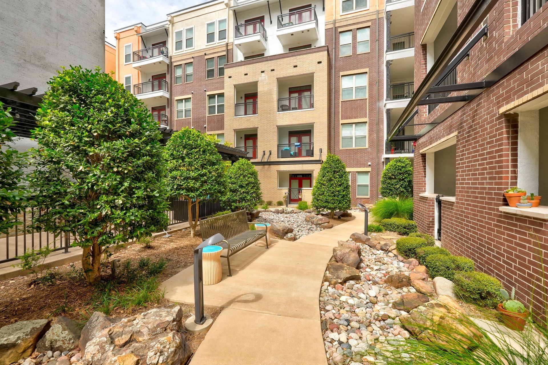 A brick building with a walkway leading to it surrounded by trees and rocks.