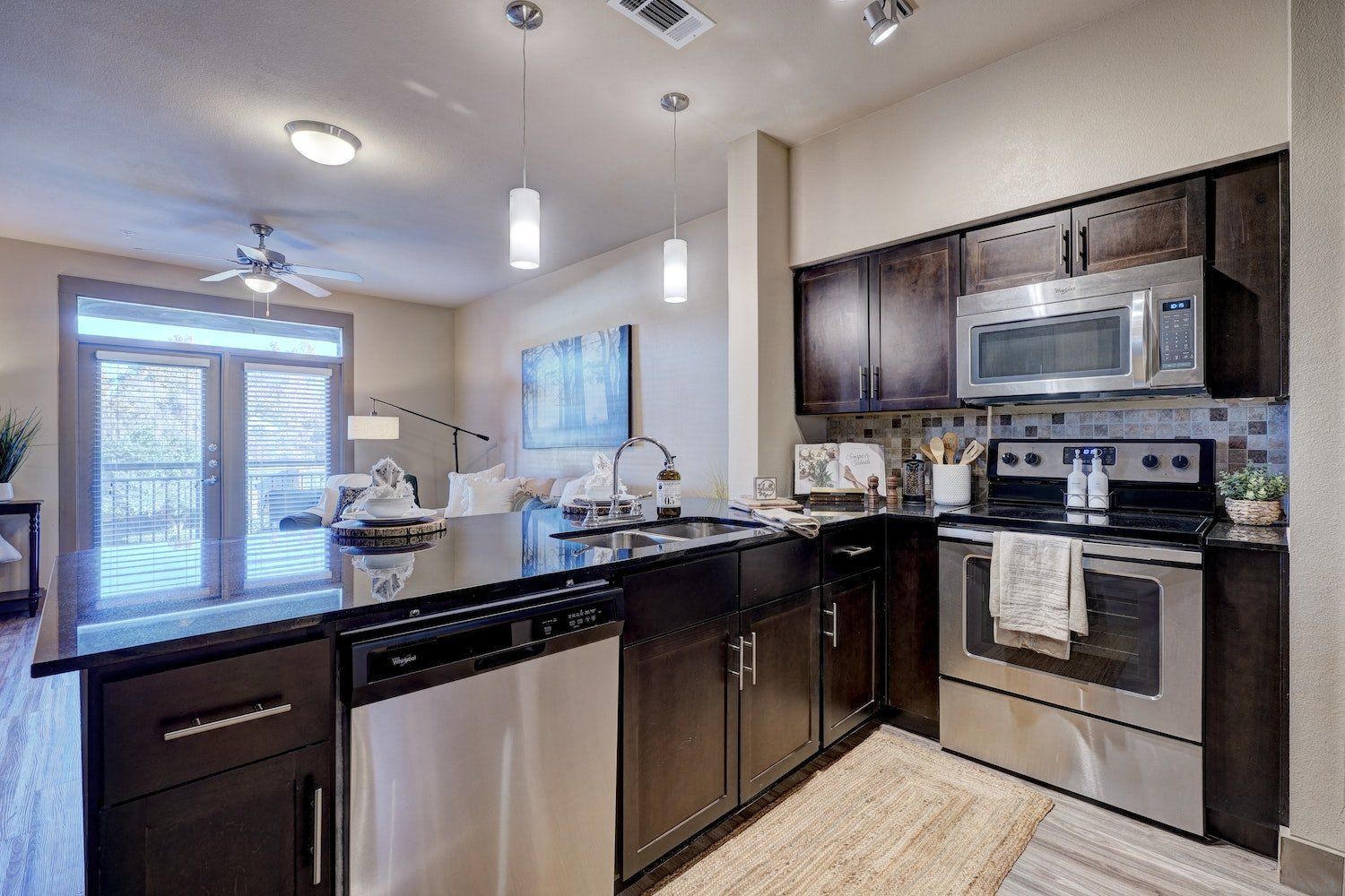 A kitchen with stainless steel appliances and black cabinets.