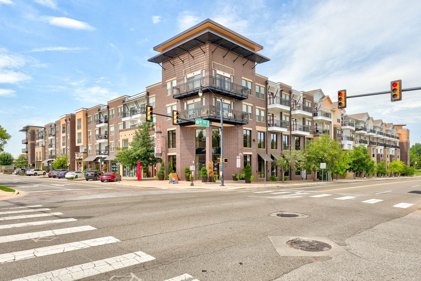 A large apartment building is sitting on the corner of a city street.