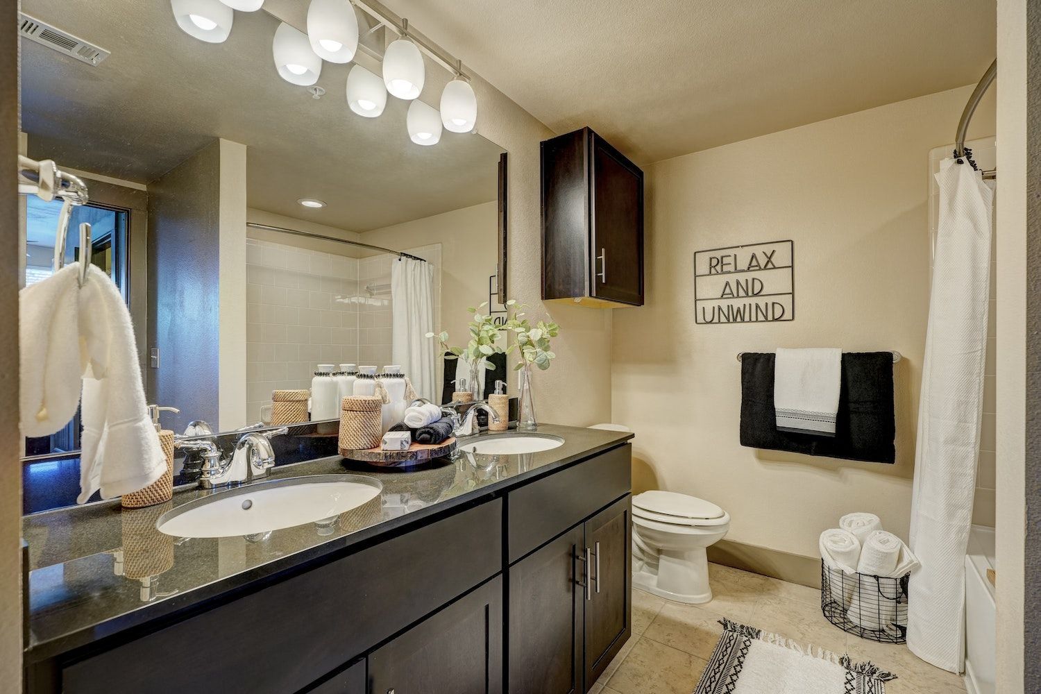 A bathroom with two sinks, a toilet, and a large mirror.