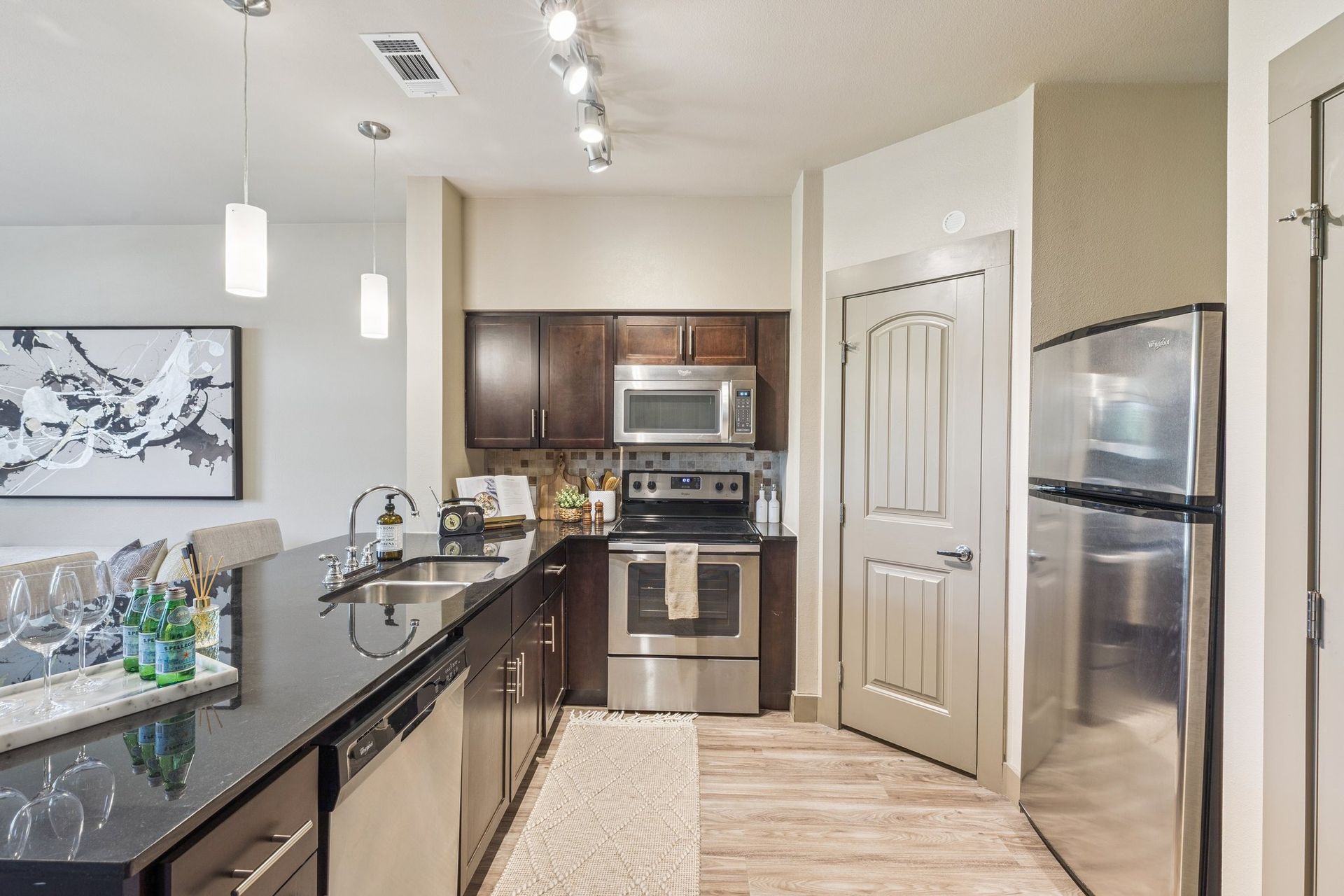 Modern kitchen with black countertops, stainless steel appliances, and dark wood cabinets.
