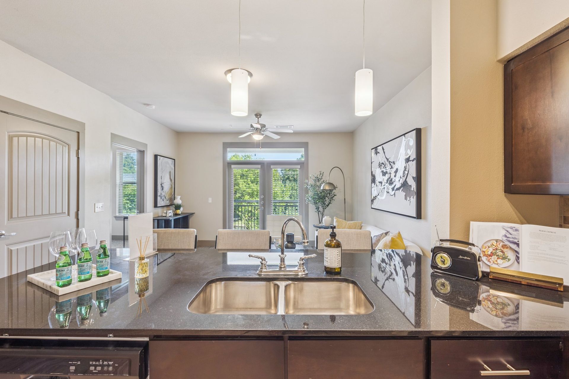 Kitchen with granite countertop, sink, and view into the living space with balcony.