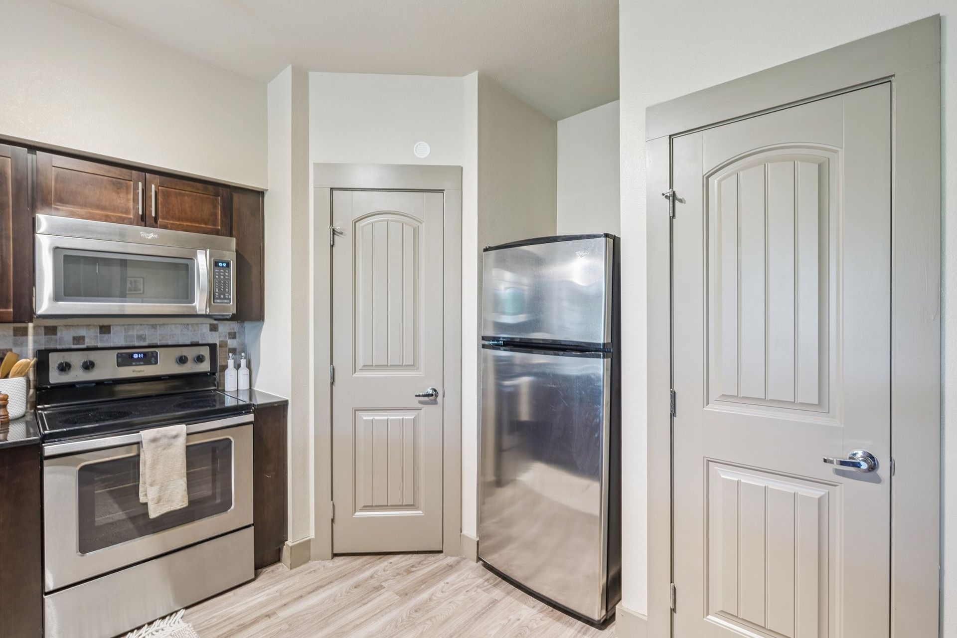 Kitchen with stainless steel appliances, dark cabinets, and light-colored doors.