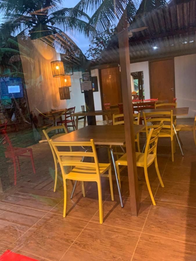 Um restaurante com cadeiras e mesas amarelas com uma palmeira ao fundo.