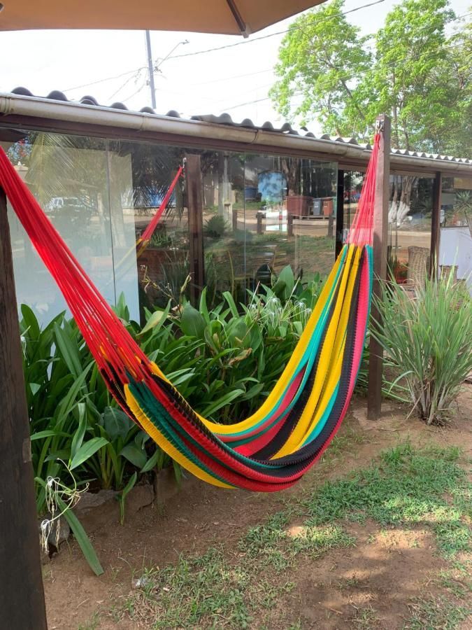 Uma rede colorida está pendurada em um poste de madeira em um jardim.