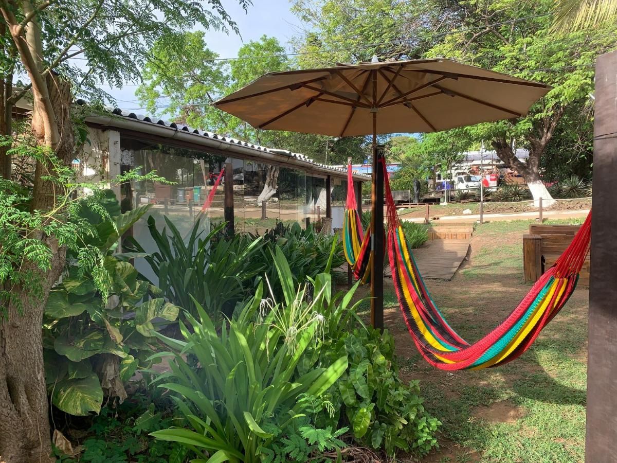 Uma rede colorida está sob um guarda-chuva em um jardim.