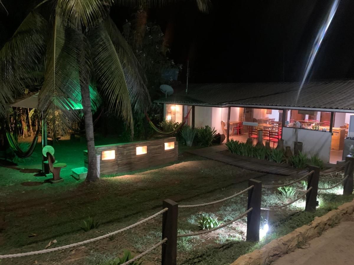 Uma casa iluminada à noite com palmeiras ao fundo.