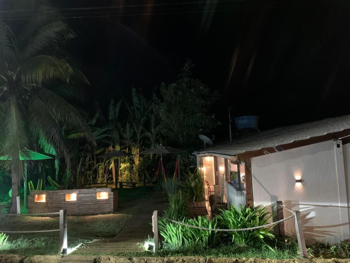 Uma casa iluminada à noite com palmeiras ao fundo.