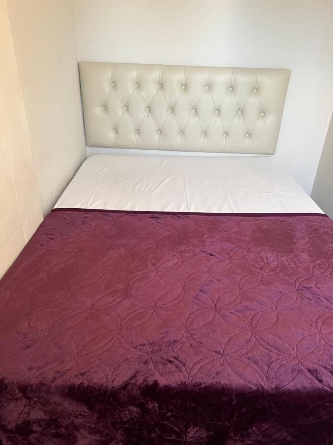 Uma cama com um cobertor roxo e uma cabeceira branca.
