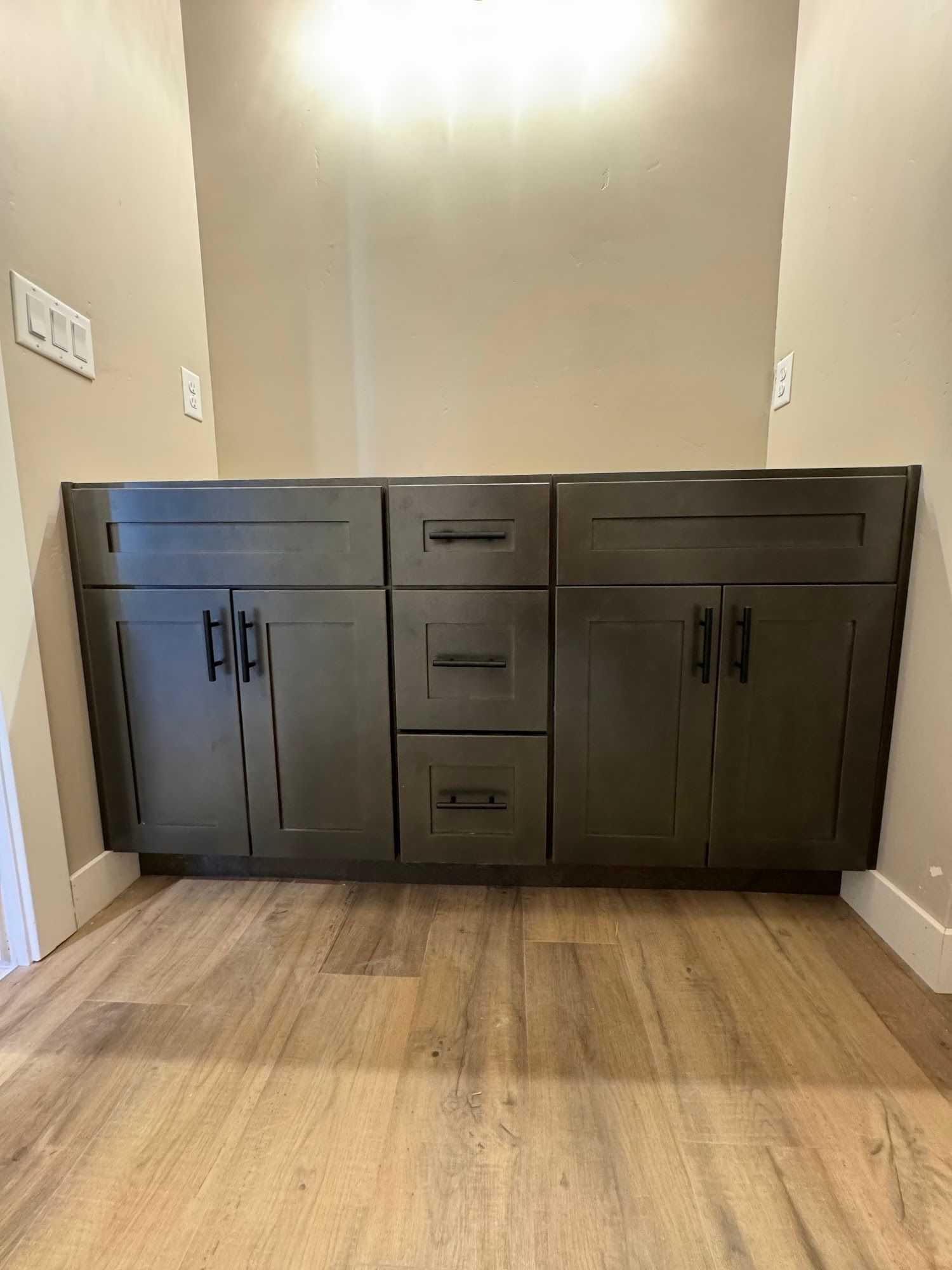 Wooden bathroom vanity with drawers and cabinets installed against a textured blue wall.