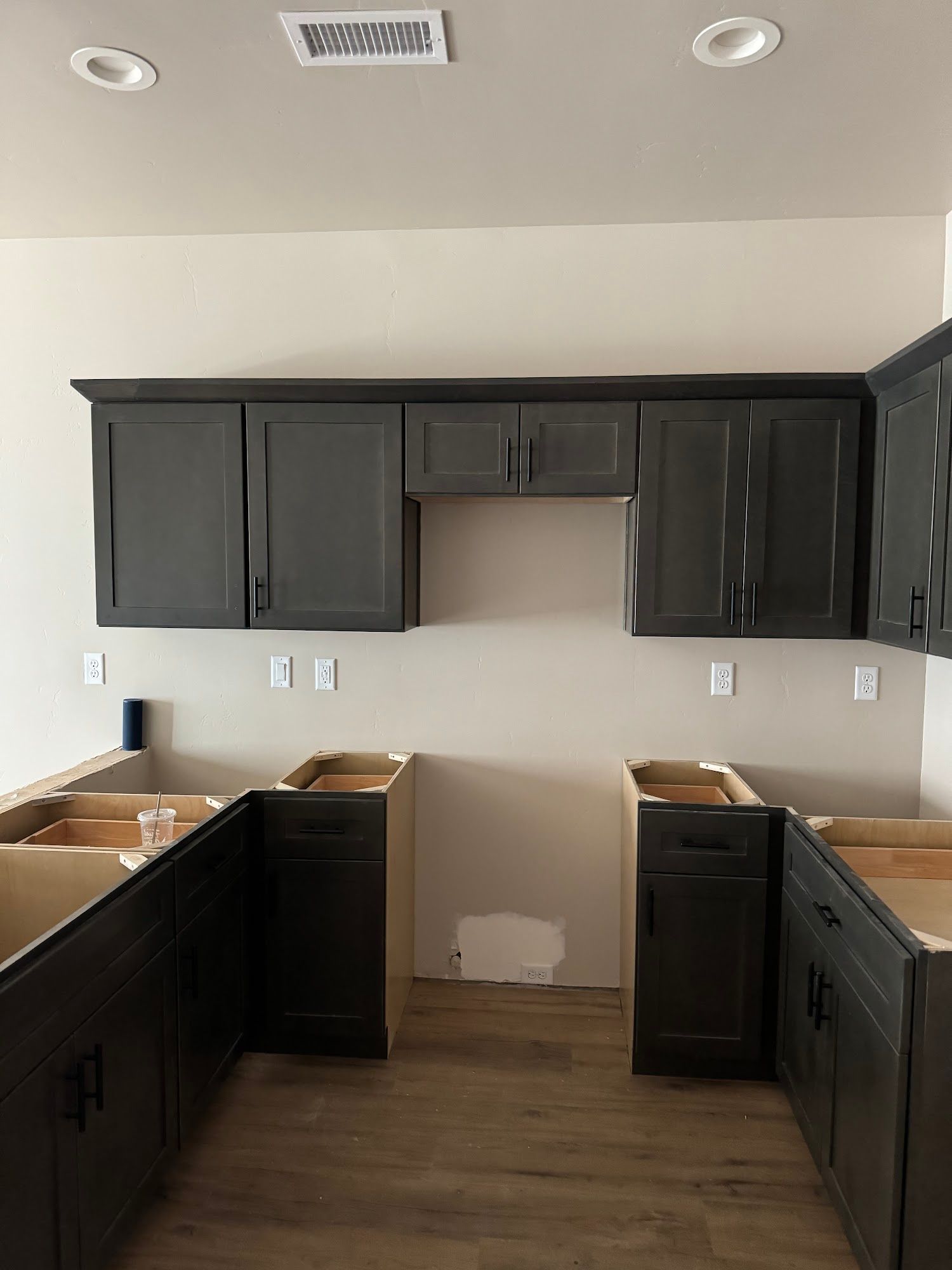 Kitchen cabinets in various stages of installation, with a dark gray finish.
