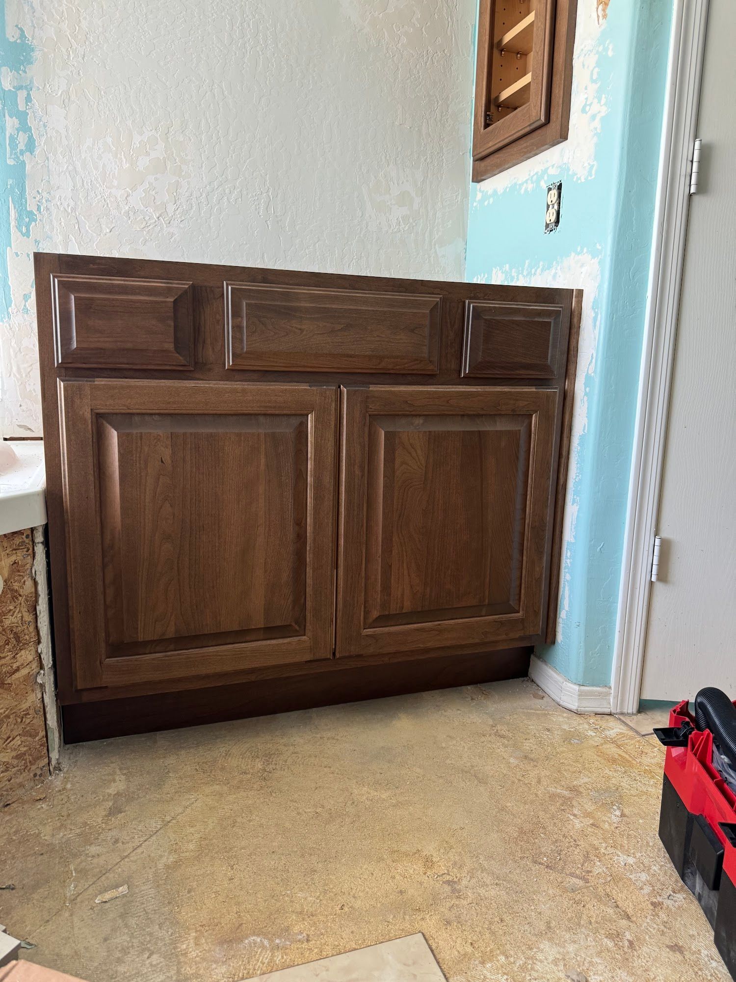 Brown bathroom vanity cabinet against peeling blue and white wall.