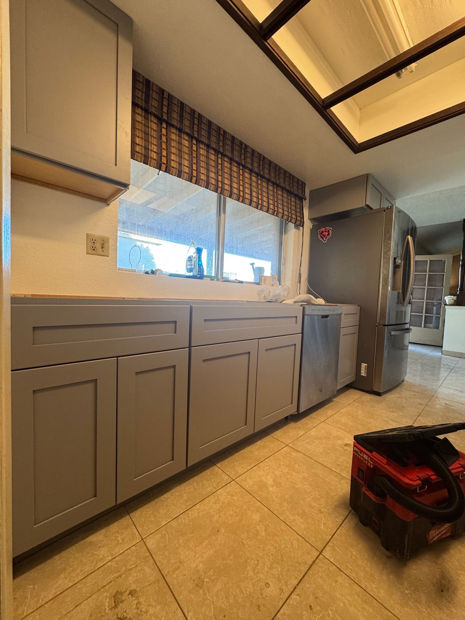 Gray kitchen cabinets and appliances; window with blinds.