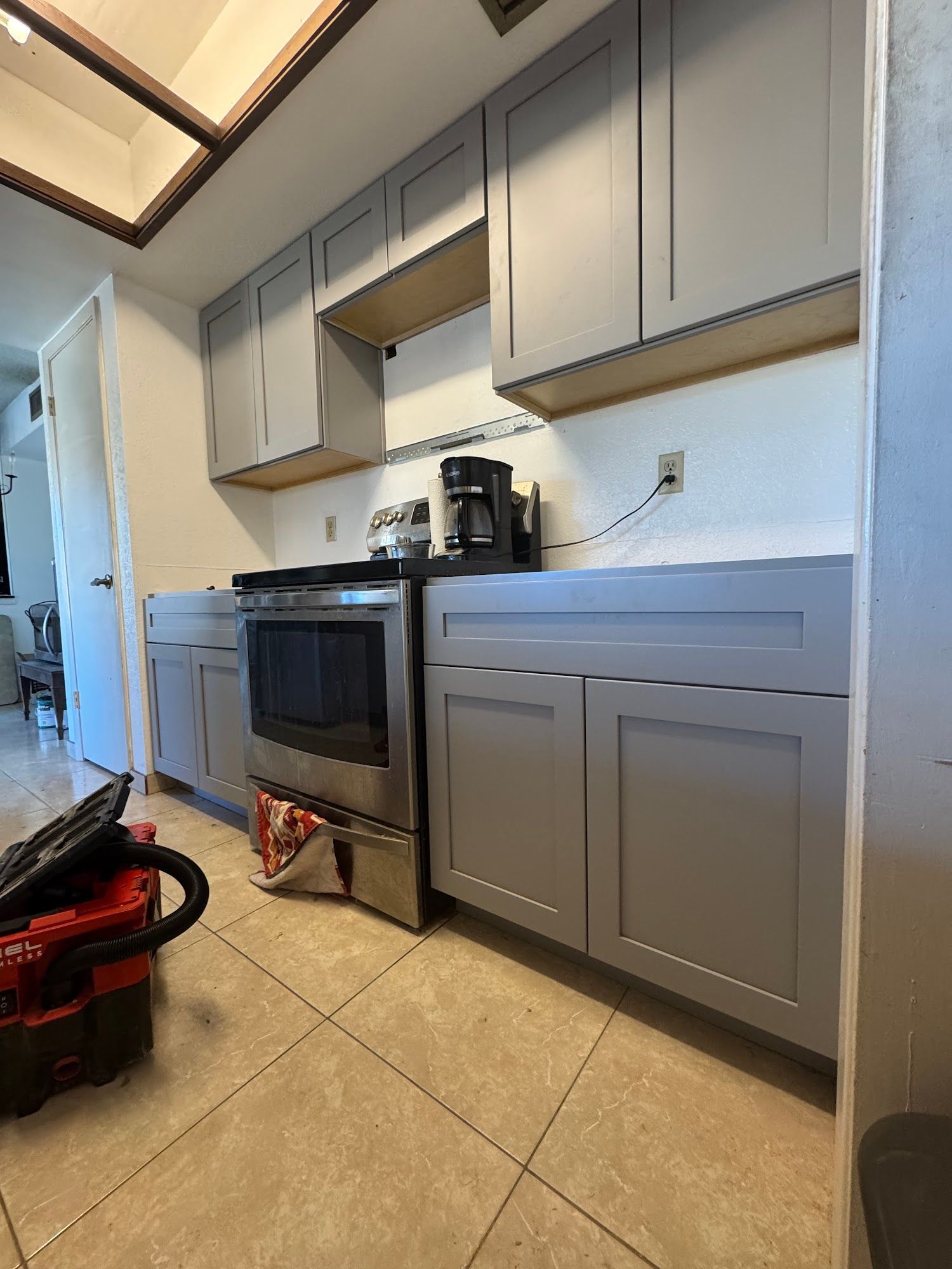 Gray kitchen cabinets, oven, and tile floor, under construction.