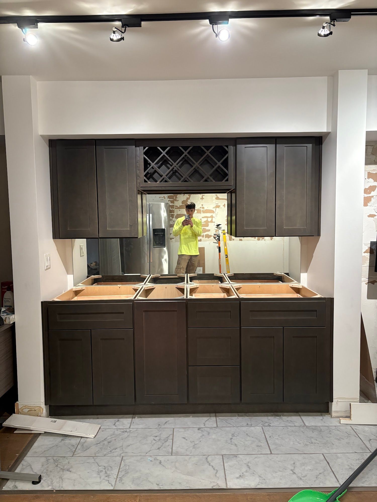 Dark gray cabinets installed, with wine rack, mirror, and a person reflected.