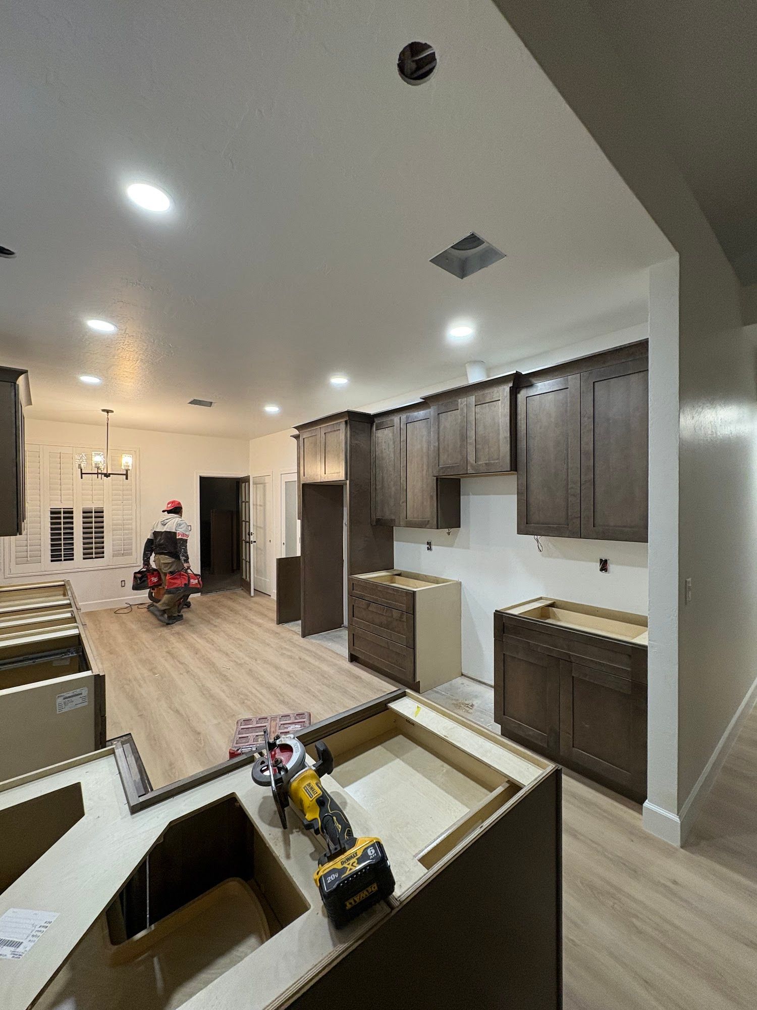 Kitchen renovation in progress: new brown cabinets being installed on white walls, tools on the floor.