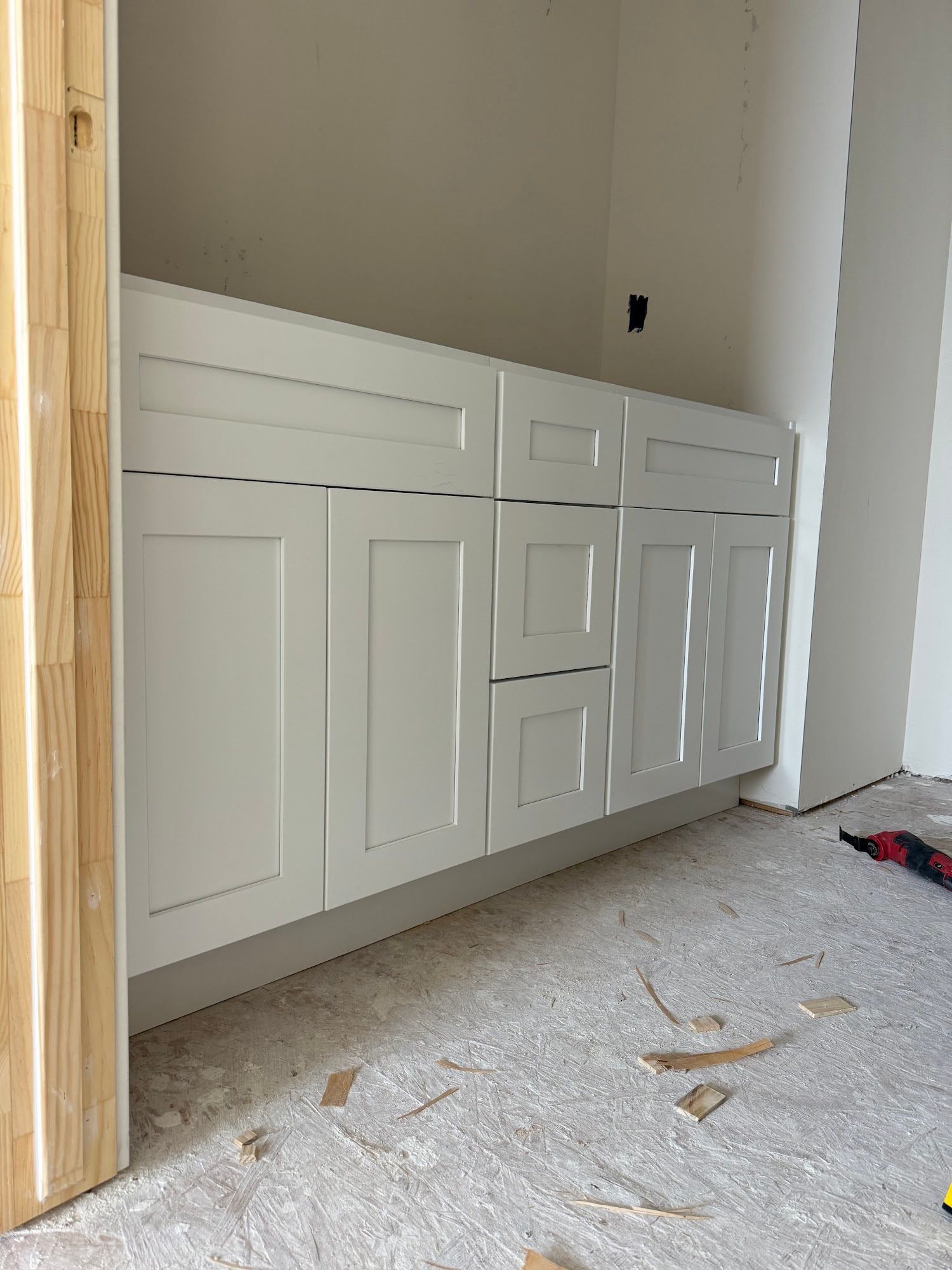 White bathroom vanity with shaker-style cabinet doors and two drawers installed against a light wall.