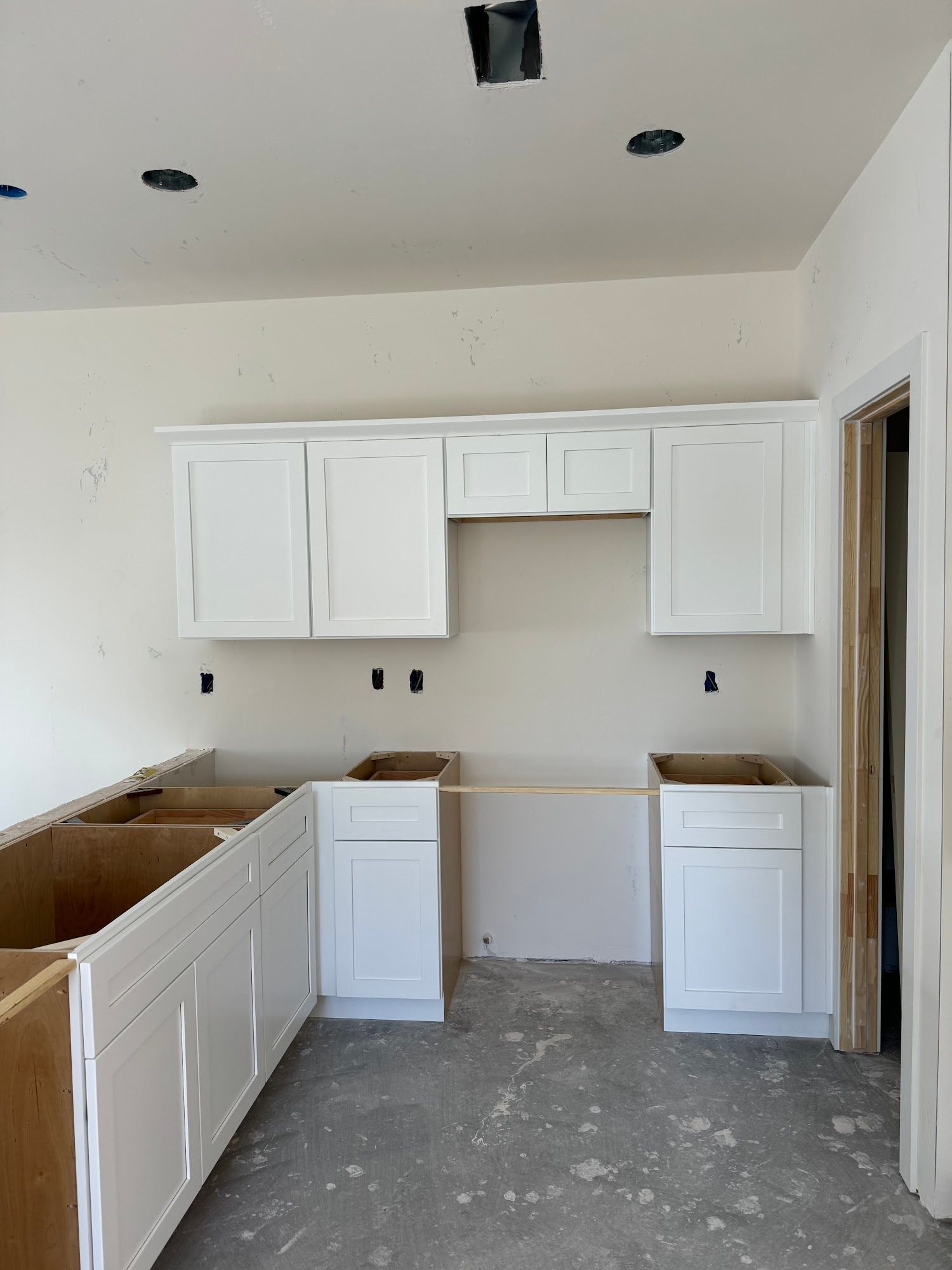 Gray kitchen cabinets, oven, and tile floor, under construction.