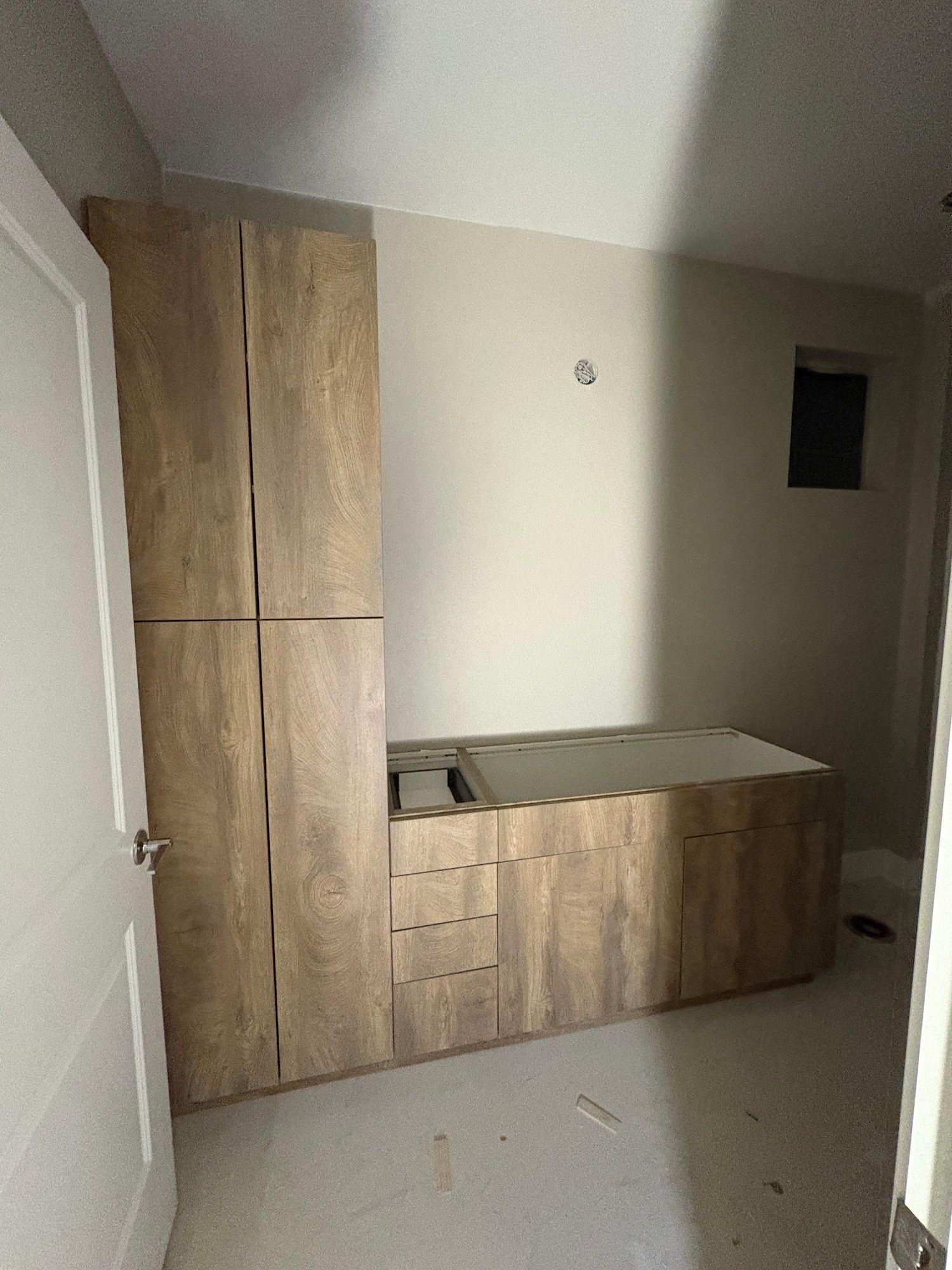 Wooden bathroom cabinetry under construction with a tall cabinet and lower vanity.