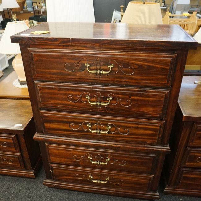 A wooden chest of drawers with gold handles