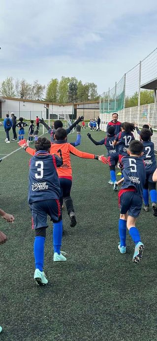 Un groupe de jeunes garçons jouent au football sur un terrain.