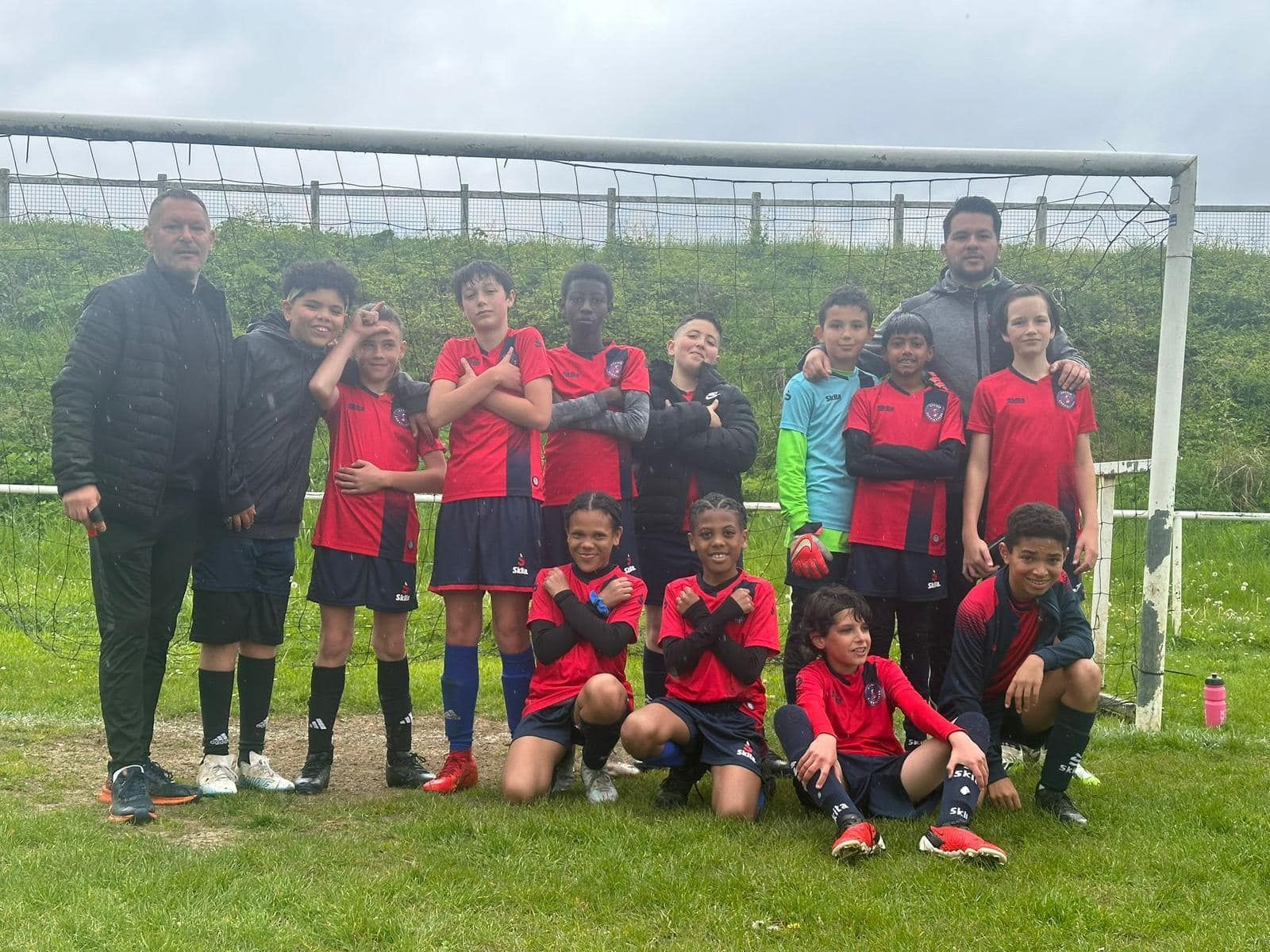 Un groupe de jeunes garçons posent pour une photo sur un terrain de football.