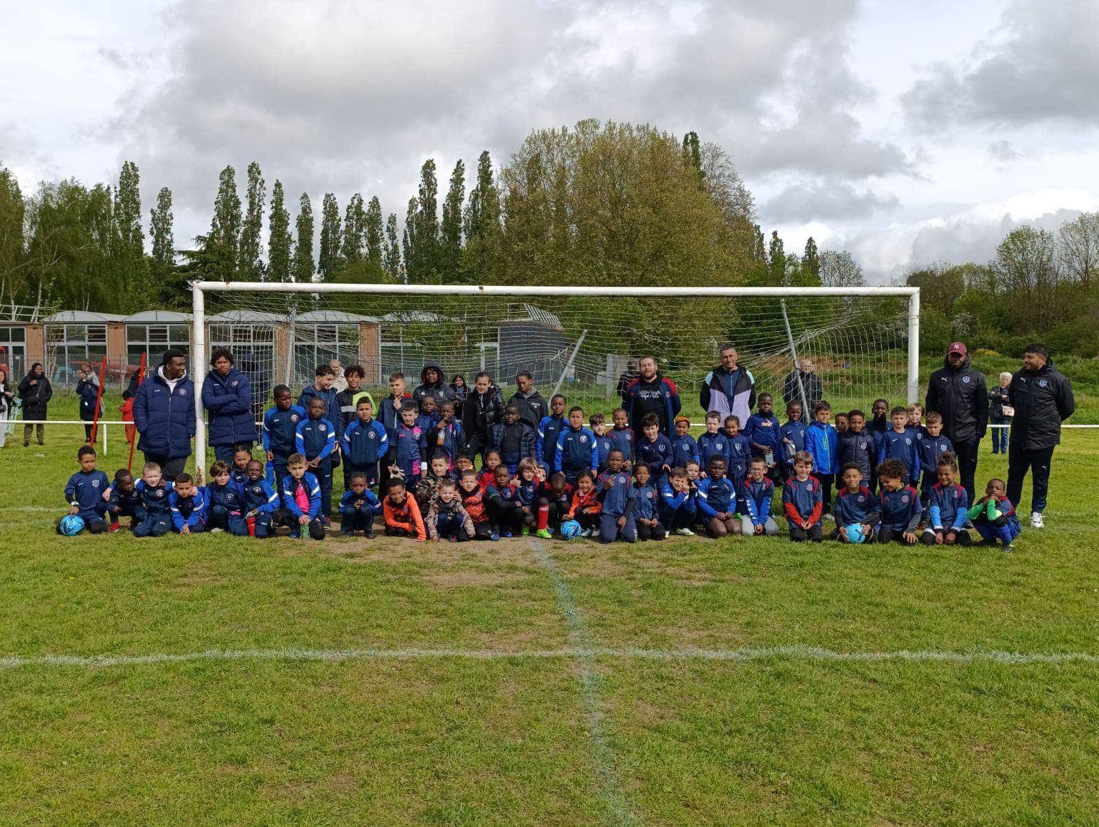 Un groupe d'enfants pose pour une photo sur un terrain de football.