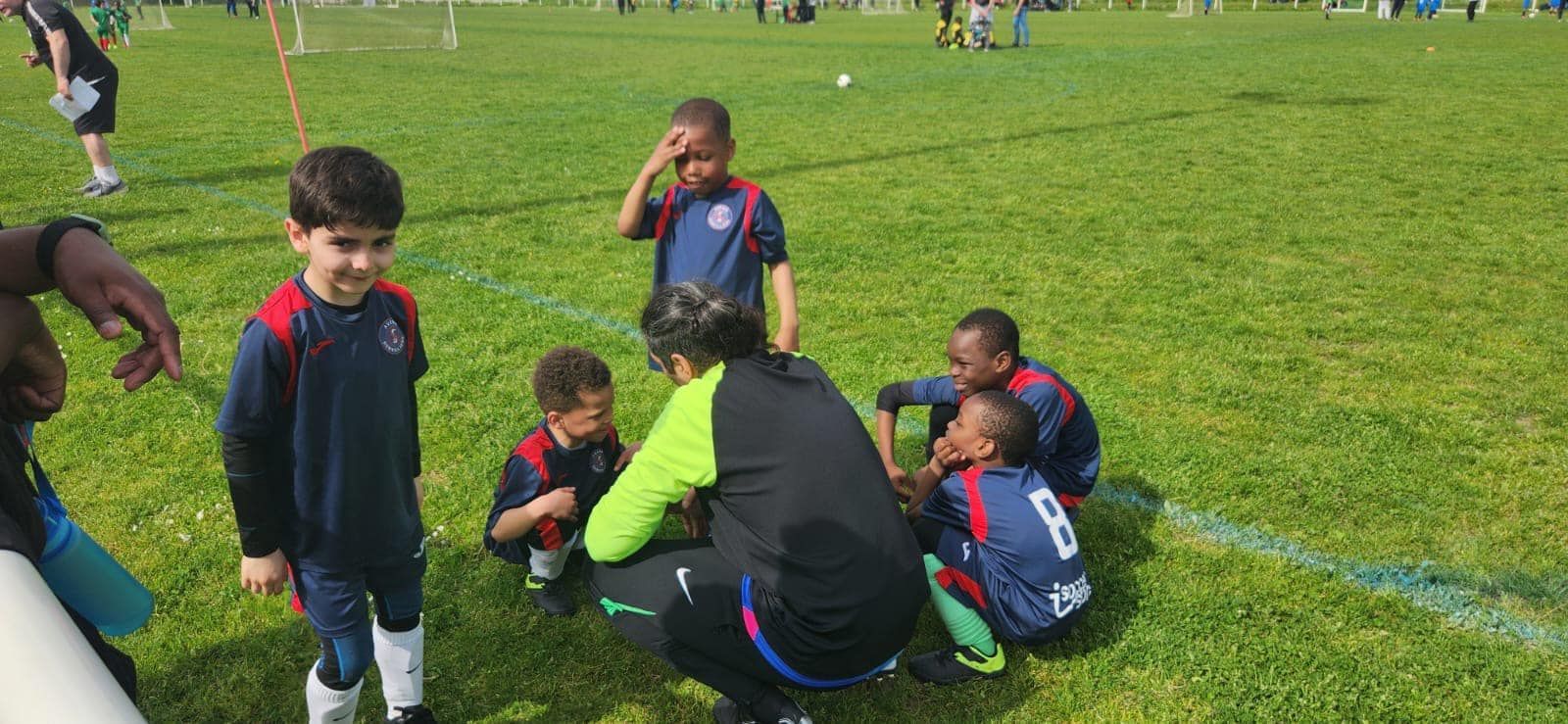 Un groupe de jeunes garçons jouent au football sur un terrain.