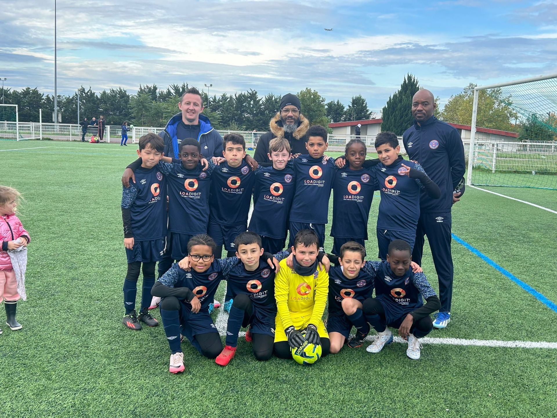 Un groupe de jeunes garçons jouent au football sur un terrain.