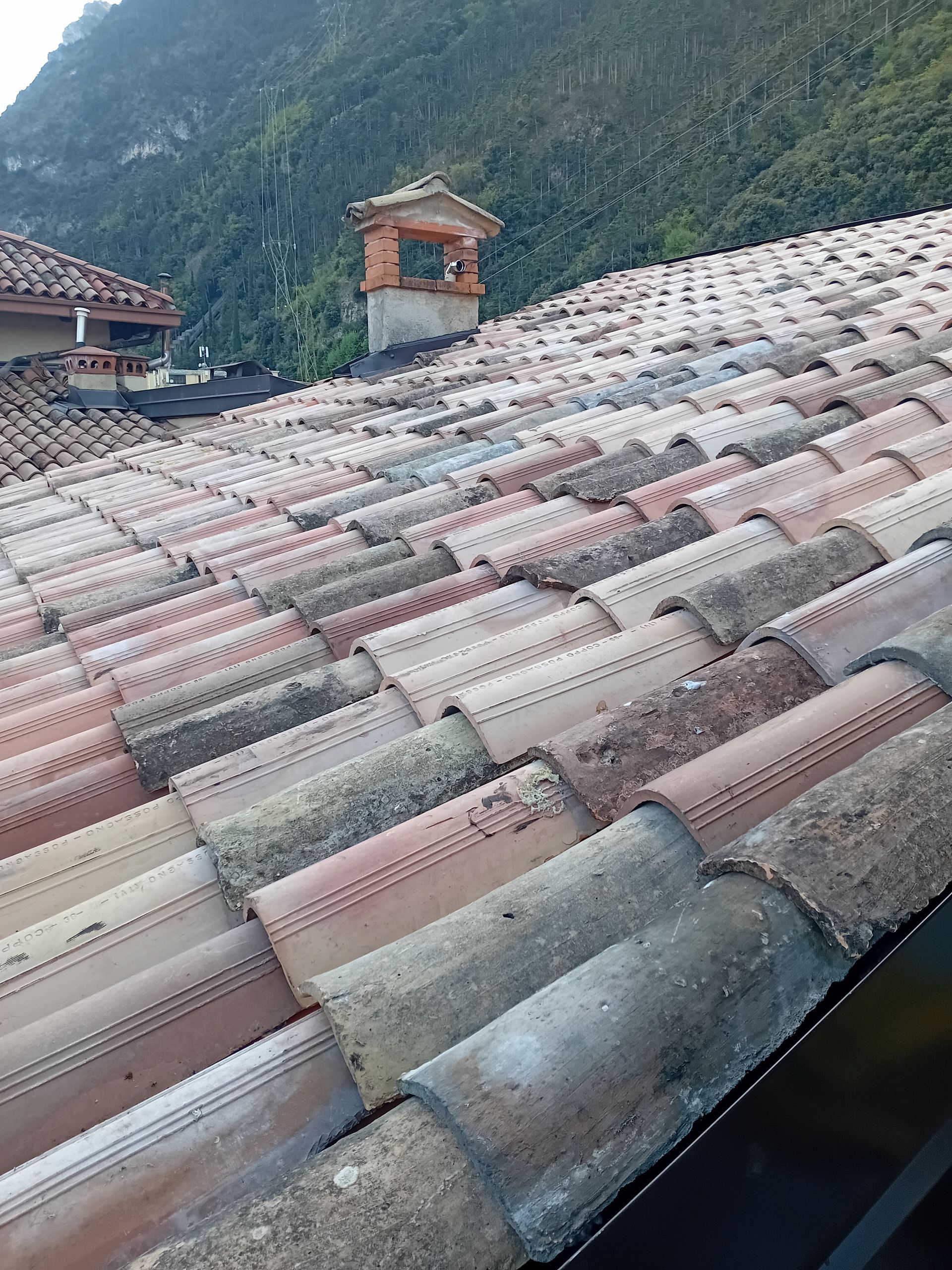 Un primo piano di un tetto di tegole con un camino in cima.