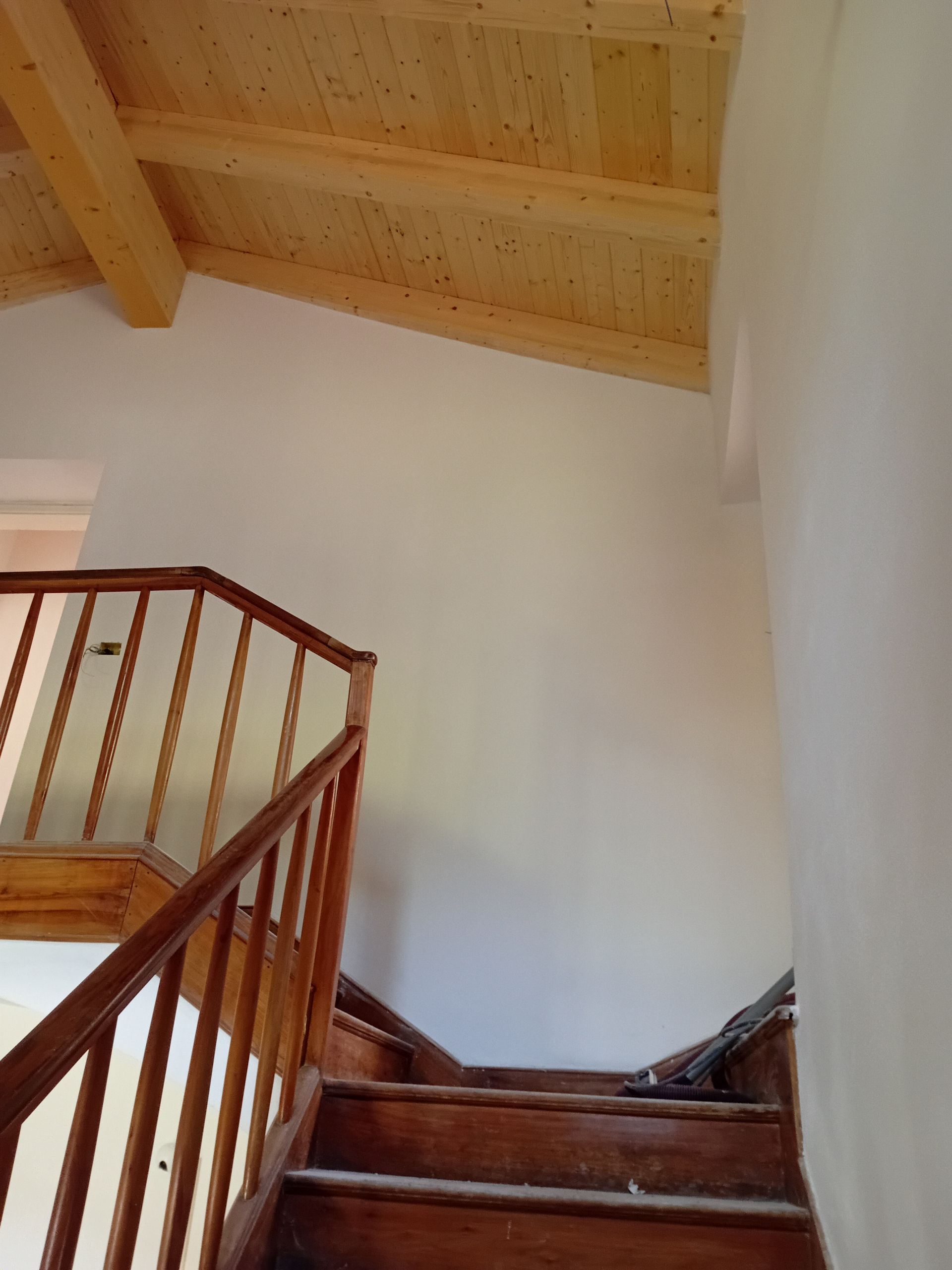 Una scala con ringhiera in legno e soffitto in legno