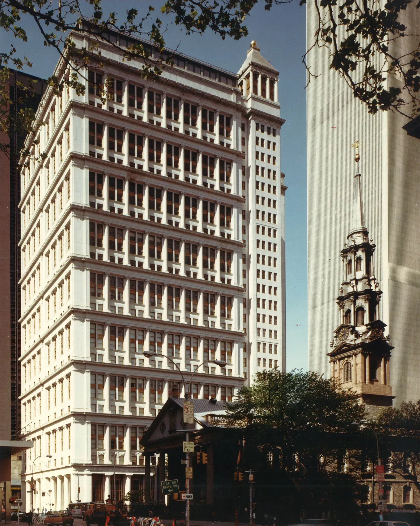 White skyscraper next to a church with a tall steeple in a city setting.