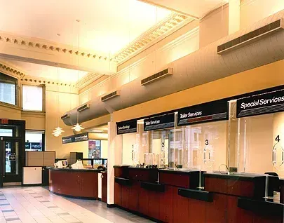 Interior view of a post office with service counters and a long, decorative ceiling element.