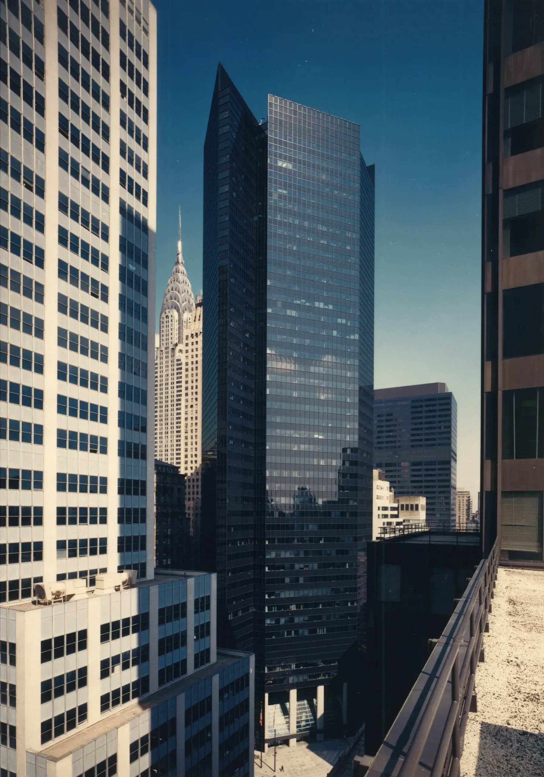 Skyscrapers in a city, framed by other buildings, with a view of the sky.