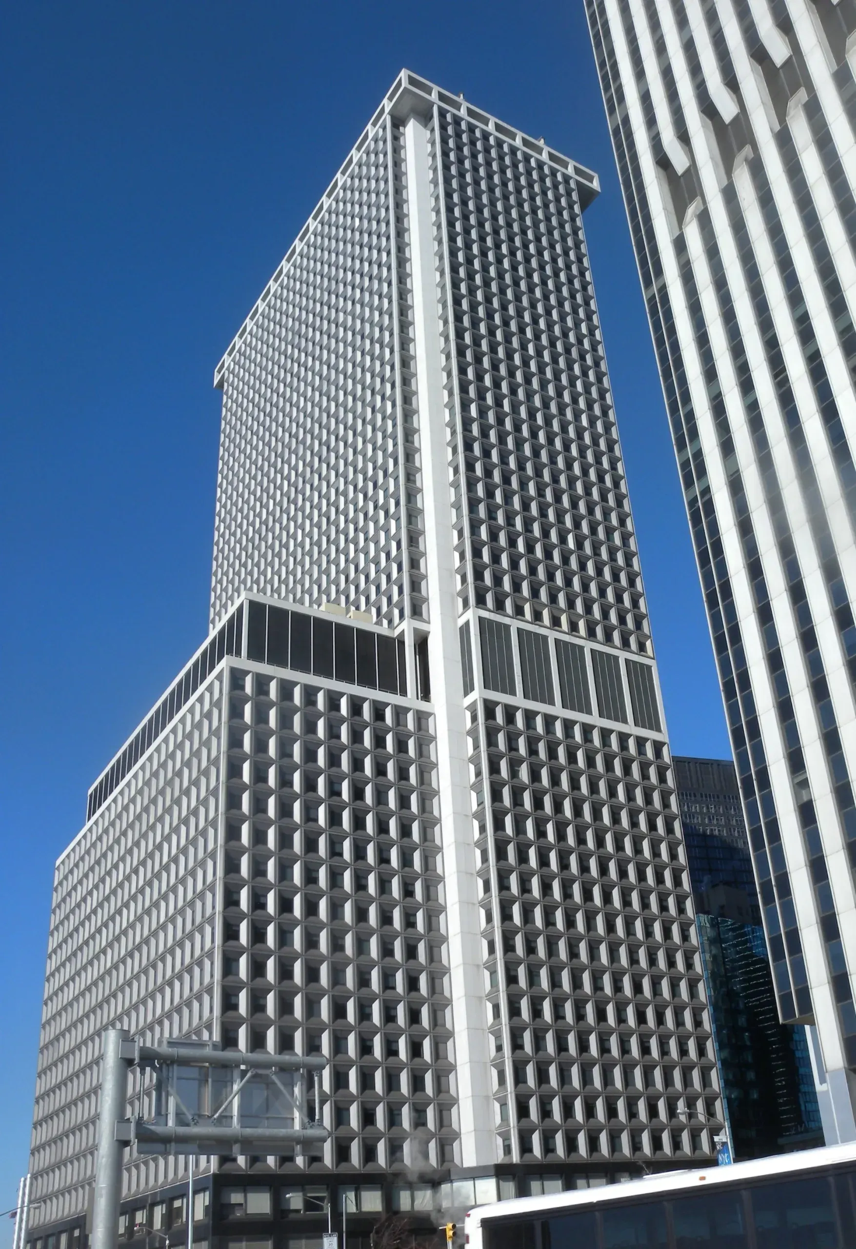 Tall skyscraper against a clear blue sky. The building is light grey with a grid of windows.