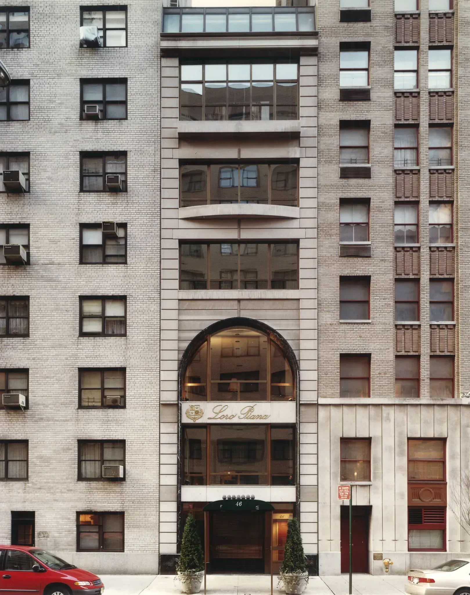 A New York City apartment building with a recessed arched entrance, flanked by brick and stone facades.