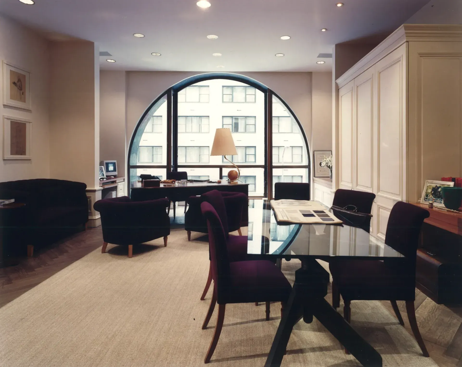 An office interior with a large arched window overlooking a city.