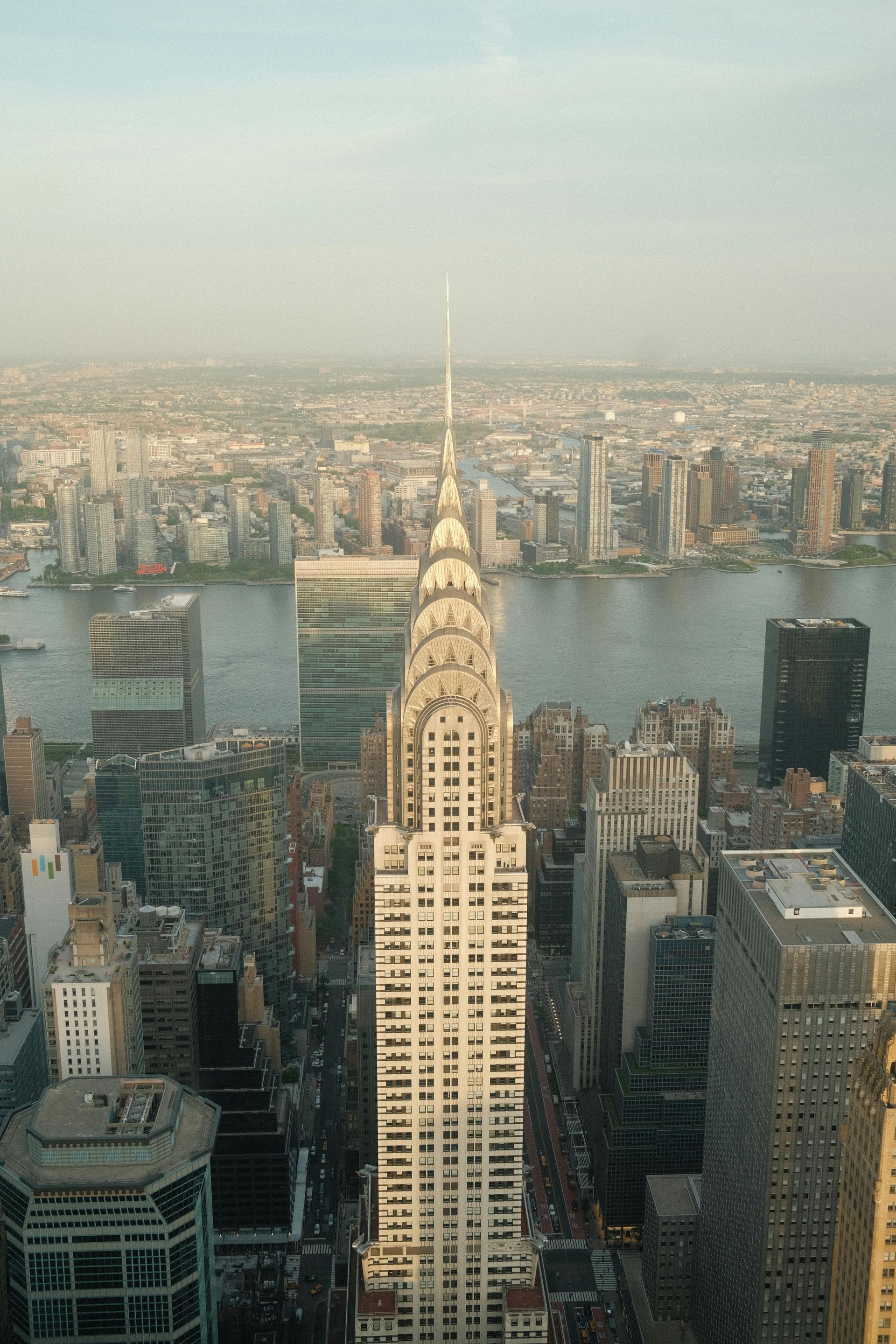 Chrysler Building in New York City, viewed from above, with surrounding cityscape and river in the background.