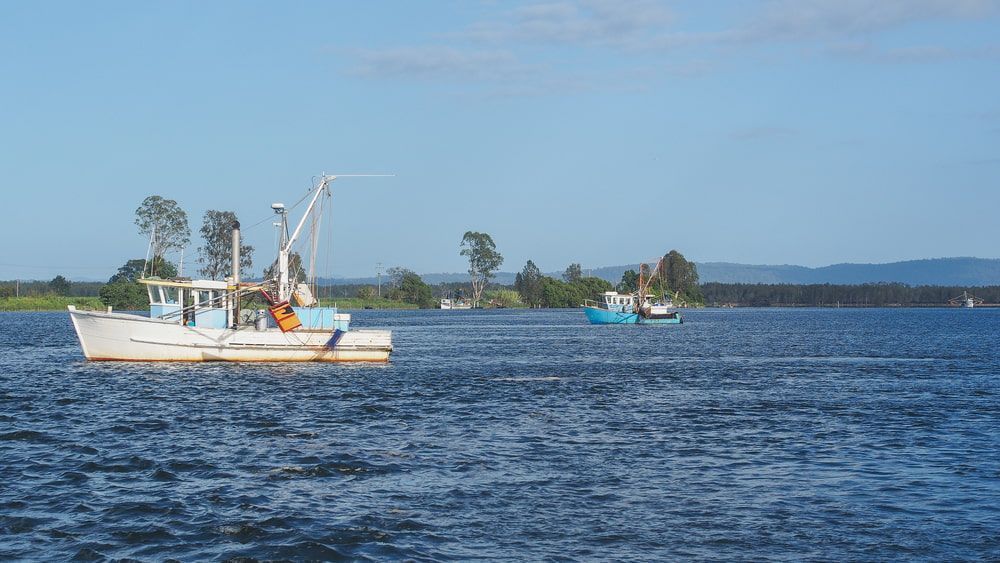 A Boat is Floating on Top of a Large Body of Water — Jaya Rose Earthworks and Landscape Contractors In Maclean, NSW