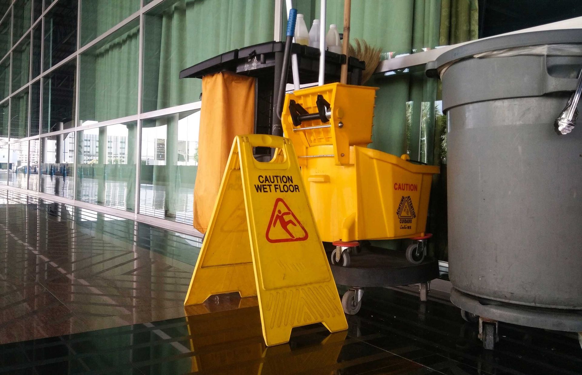 Caution sign of wet floor in the building and janitorial cart.