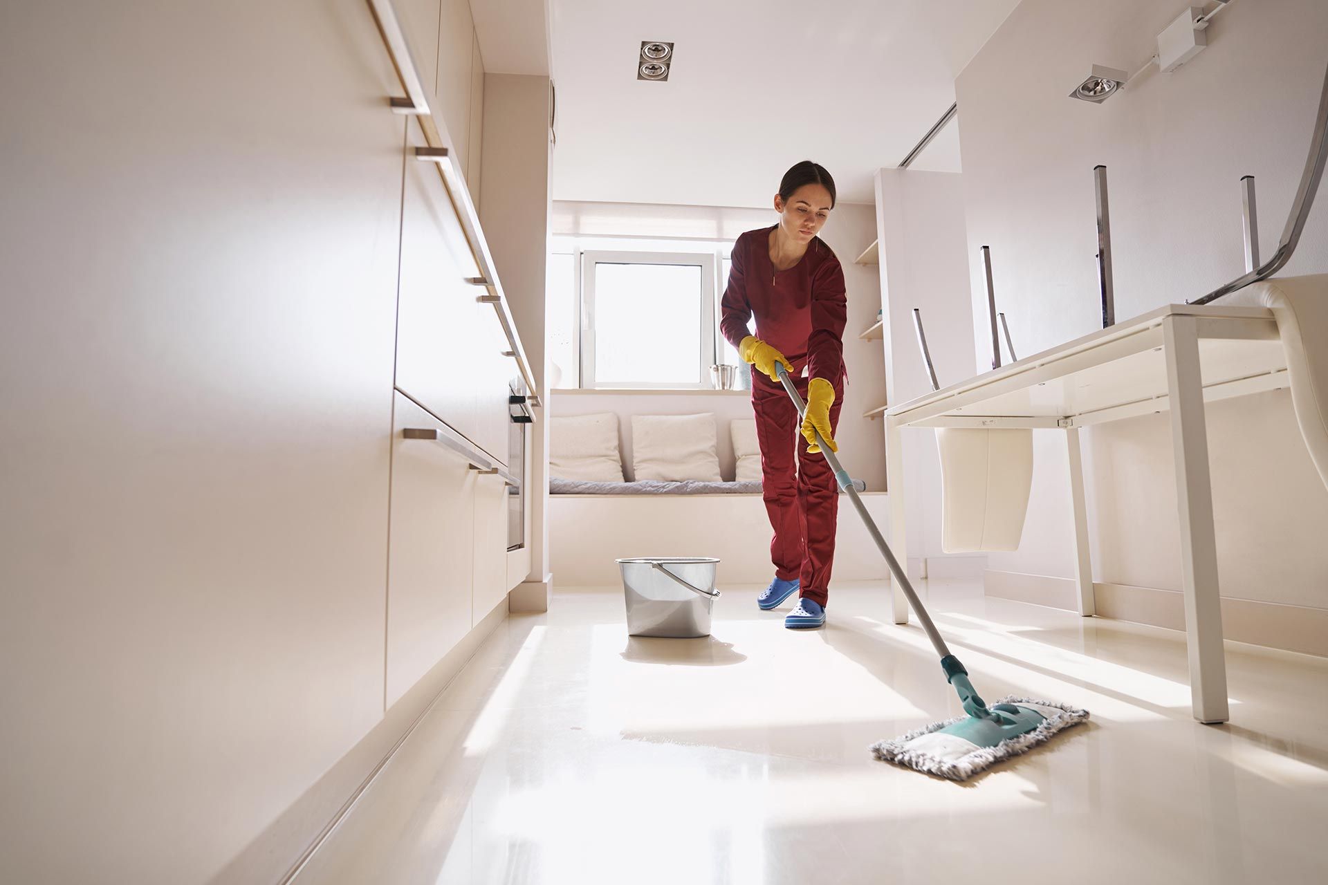Concentrated uniformed professional janitor doing wet cleaning. Concentrated uniformed professional janitor doing wet cleaning.