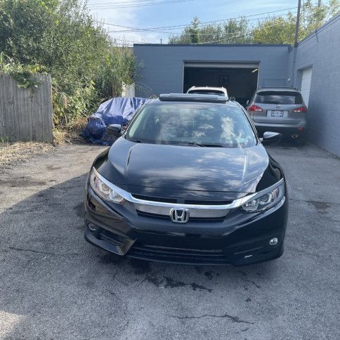 A black honda civic is parked in front of a garage.