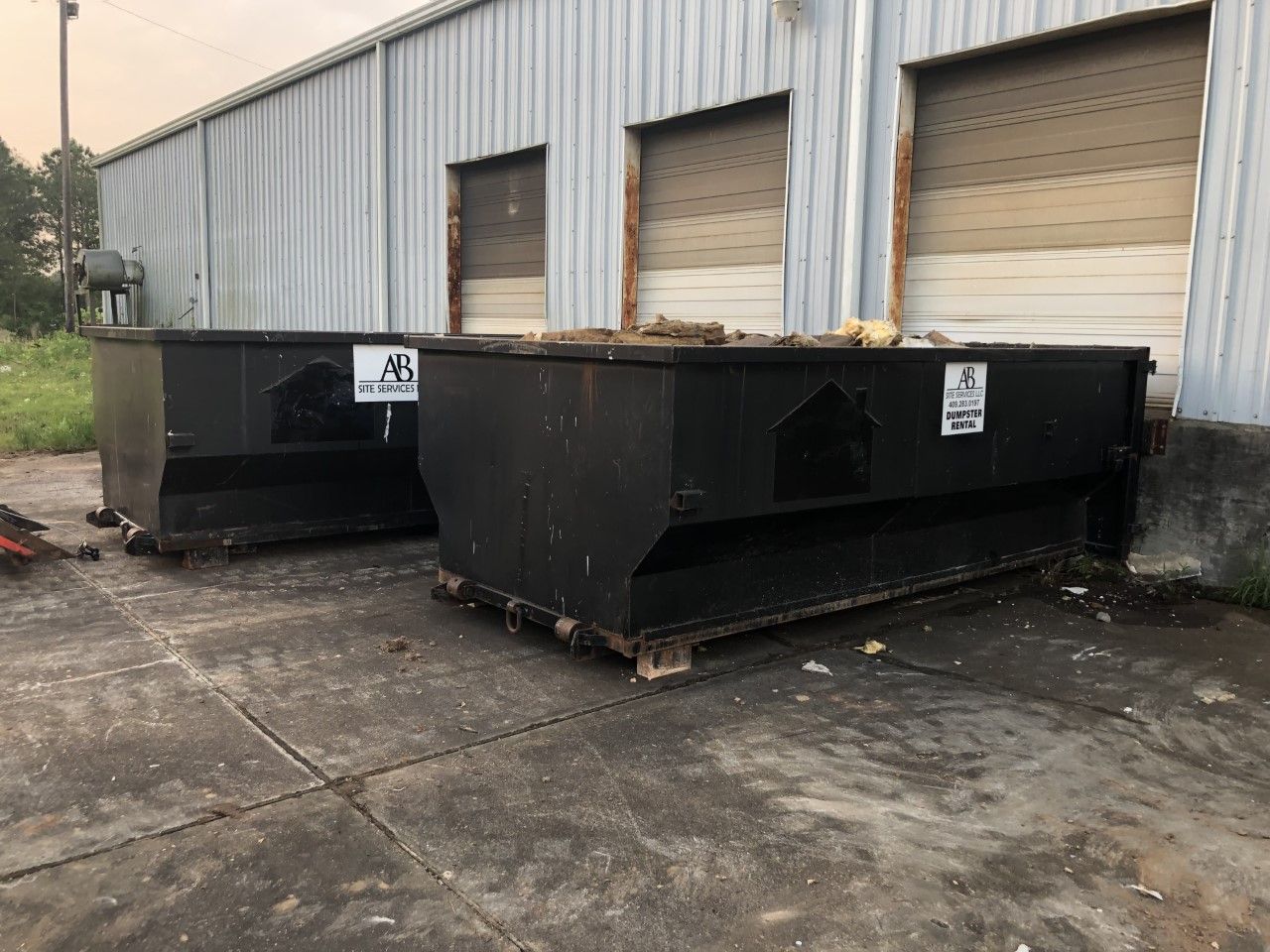 Two dumpsters are parked in front of a building.
